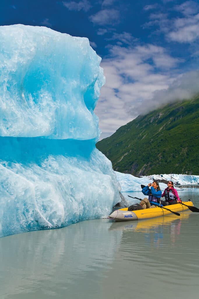 People in an inflatable canoe next to blue ice
